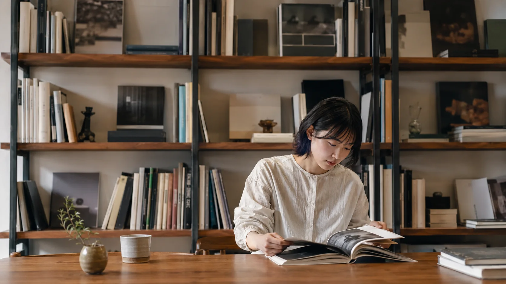 木のテーブルでデザインの写真集を読む女性